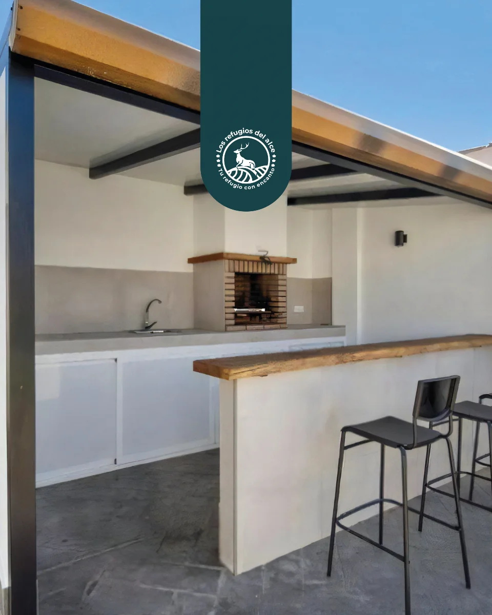 Outdoor kitchen with a built-in barbecue and a bar with stools at the accommodation