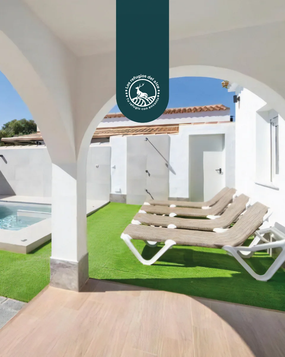 Pool and sun loungers seen through a white Andalusian arch