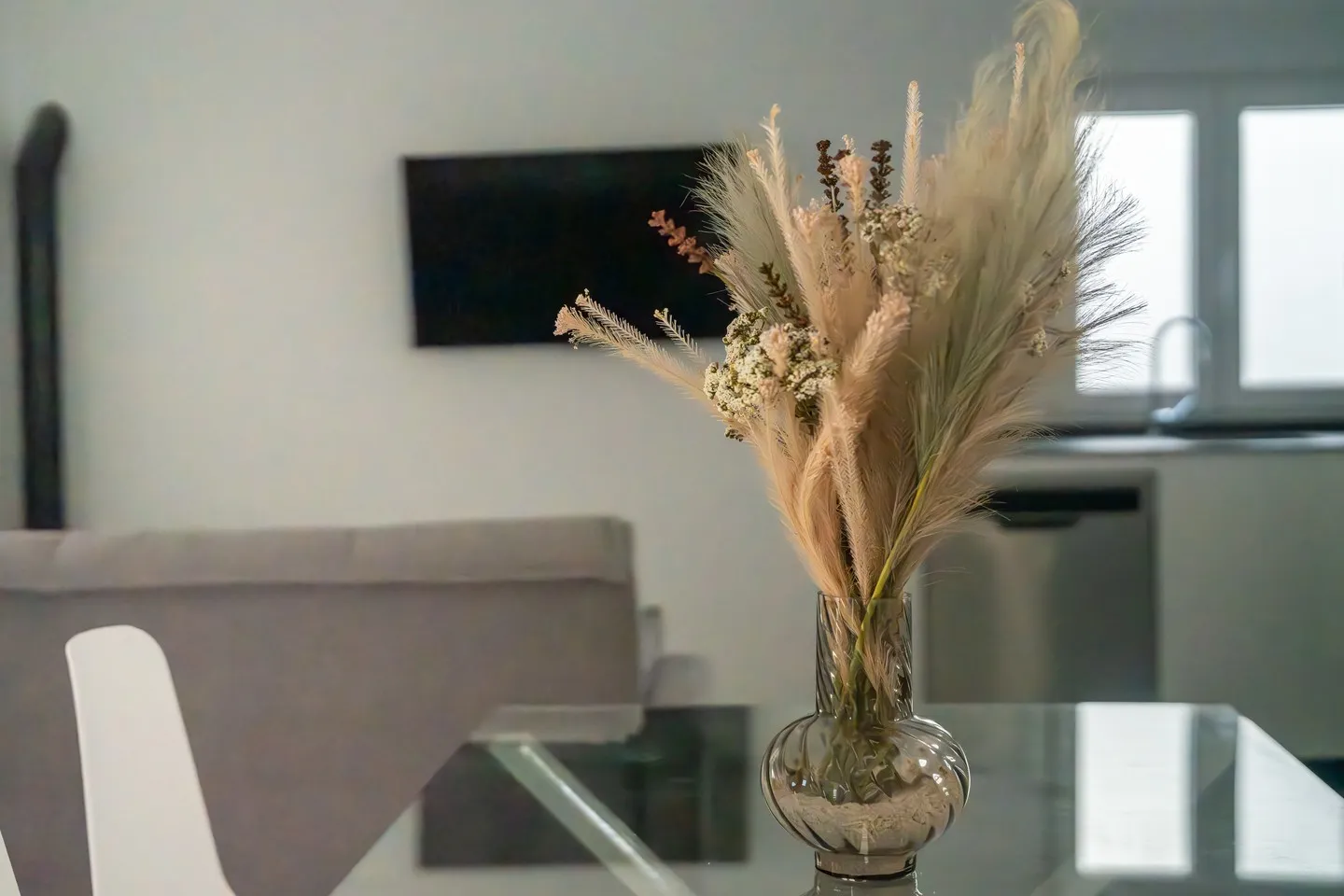 Detail of the dining area of Casa Dafer with a glass table and dried flowers