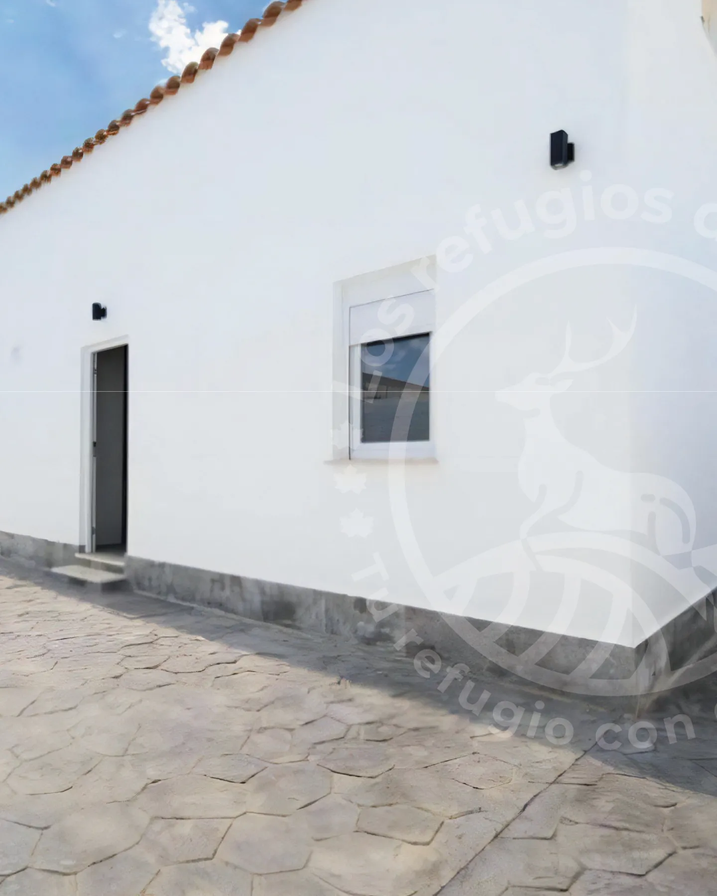 Fachada encalada con patio empedrado de un alojamiento rural para comer en Chiclana sin horarios