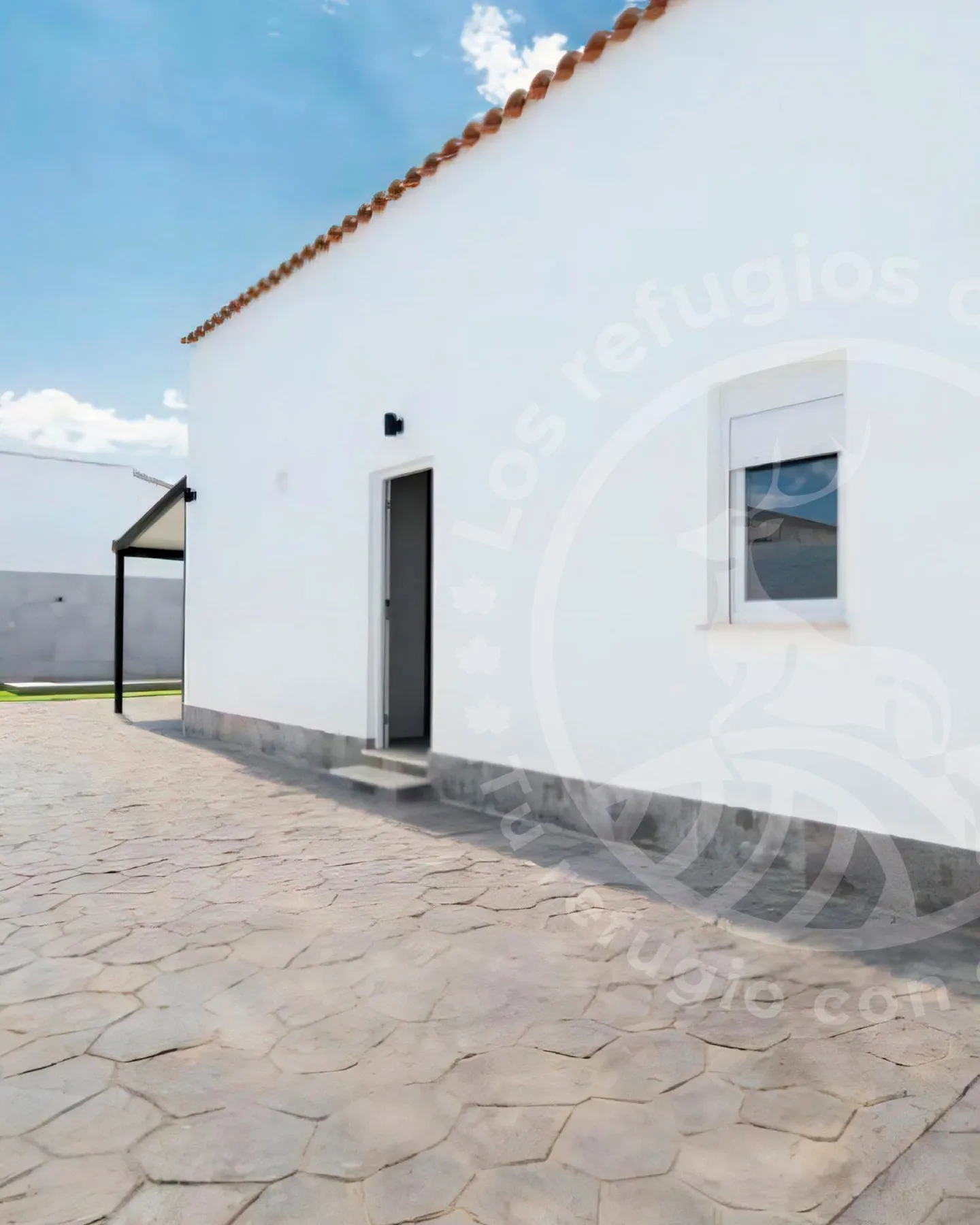 Whitewashed façade with an Arab-tile roof next to the stone patio