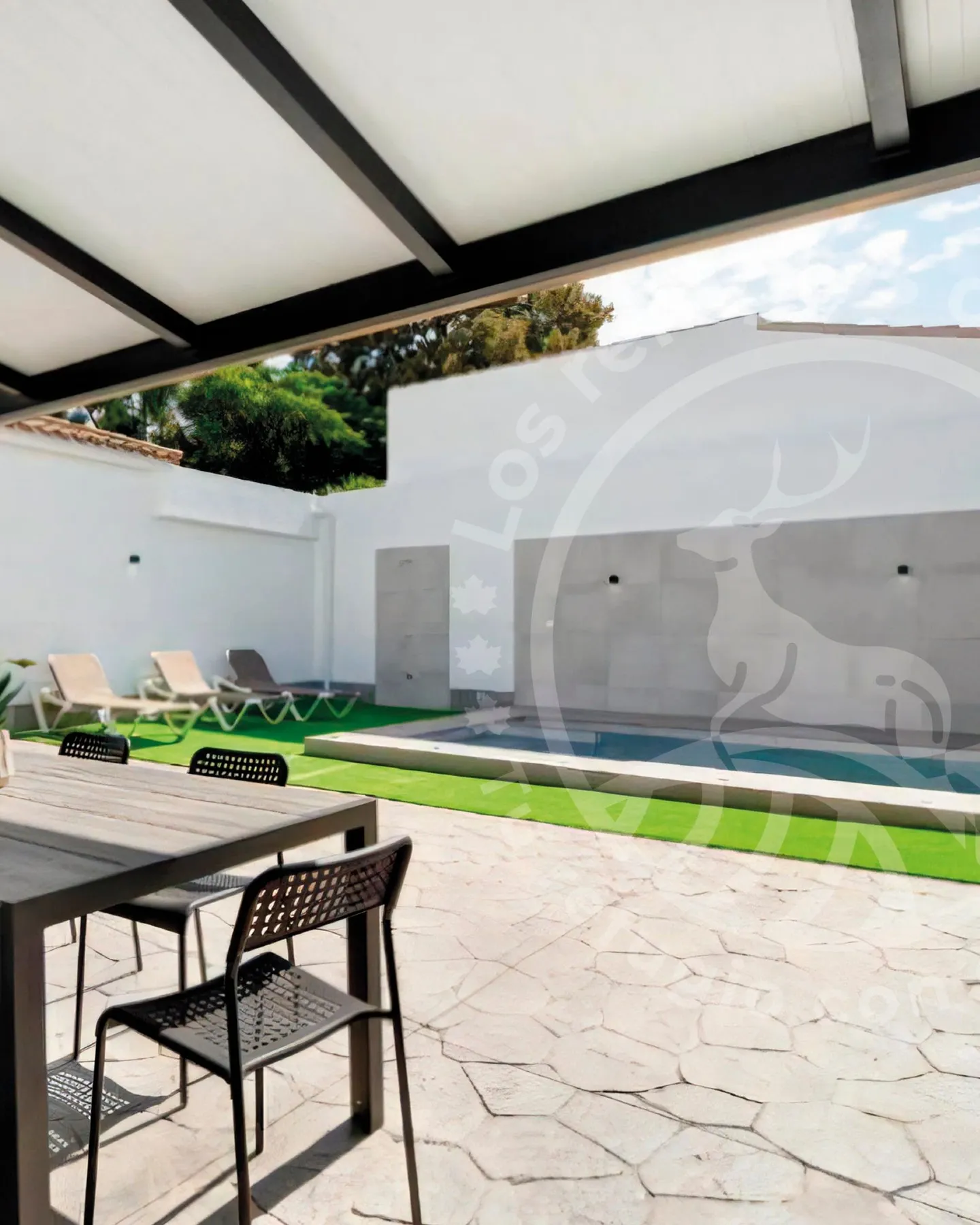View from the covered porch towards the pool, the lawn and the sun loungers